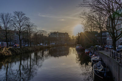 Canal amidst trees against sky at sunset