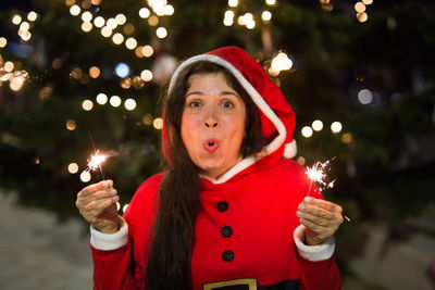 Portrait of teenage girl holding illuminated christmas tree