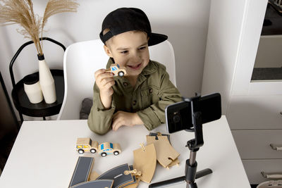 Adorable, cute, little boy blogger recording lifestyle blog, talking to camera of smartphone 