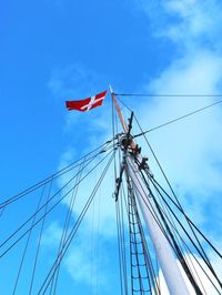 Low angle view of danish flag waving on mast against blue sky