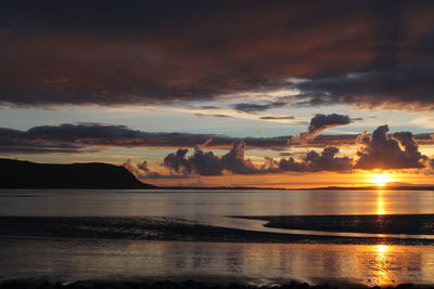 Scenic view of sea against dramatic sky during sunset