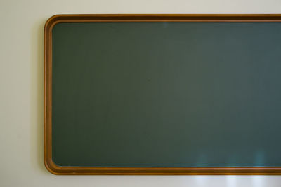 Vintage chalkboard in wooden frame on white wall