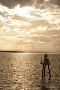 Silhouette men in sea against sky during sunset