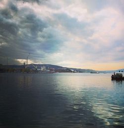 Boats in sea against cloudy sky