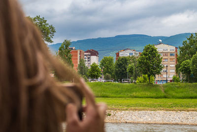 Woman hand by building against sky