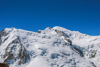 Scenic view of snowcapped mountains against clear blue sky