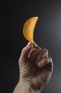 Close-up of hand holding potato chip over white background