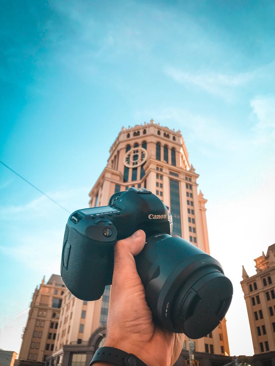 holding, building exterior, built structure, architecture, real people, photography themes, one person, sky, camera - photographic equipment, technology, photographing, activity, human hand, hand, lifestyles, human body part, unrecognizable person, city, nature, digital camera, photographer, outdoors, modern