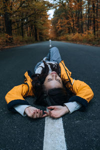 Confidence woman lying on the road with autumn tree around. new life, path choice, ambition