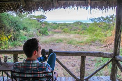 Rear view of man sitting on chair in gazebo at serengeti national park