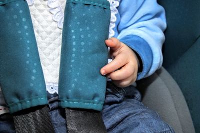Midsection of baby wearing seat belt in car