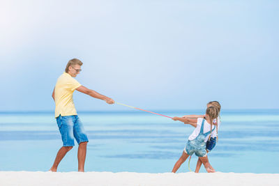 Full length of men on beach against sky