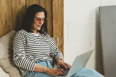 Beautiful woman is sitting at home and working on a laptop.