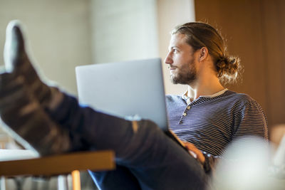 Portrait of pensive young man using laptop