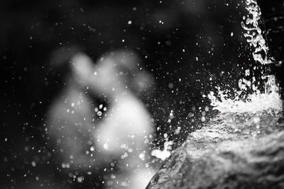 Close-up of water splashing on rock against couple kissing outdoors