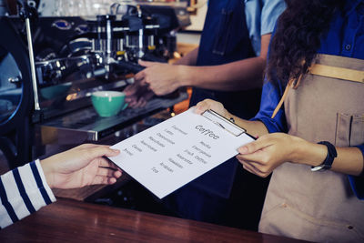 Midsection of waitress giving menu to customer