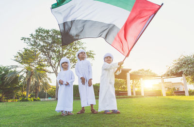 Children with united arab emirates flag standing on grassy field