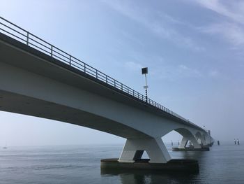 Low angle view of bridge over sea against sky