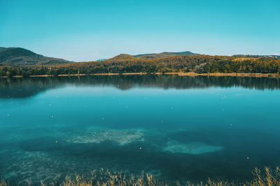 Scenic view of lake and mountains against clear blue sky