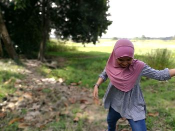 Girl wearing hijab walking on field