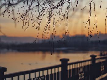 Close-up of silhouette railing against sea during sunset