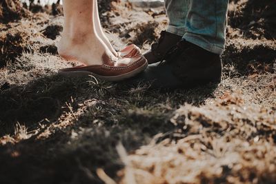 Low section of couple standing on field