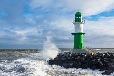 Lighthouse by sea against sky