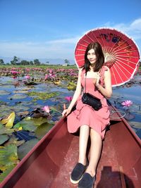 Full length portrait of woman on pink water against sky