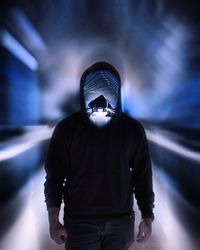 Digital composite image of man standing in illuminated corridor