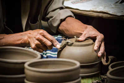 Midsection of man shaping bowl in workshop