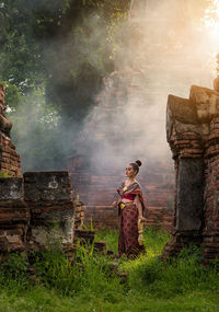 Full length of woman in traditional clothing standing by ancient temple
