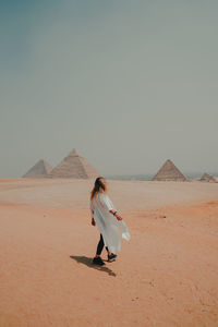 Rear view of woman standing at desert against clear sky