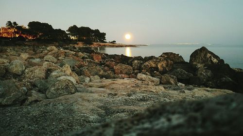 Rocks on beach against sky during sunset