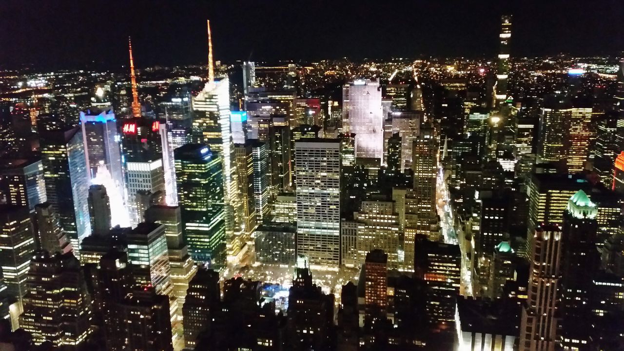 AERIAL VIEW OF ILLUMINATED CITY BUILDINGS AT NIGHT