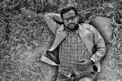 Portrait of young man sitting on land