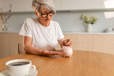 Portrait of senior man using mobile phone while sitting on table at home