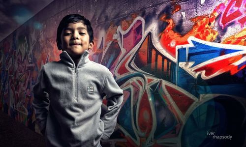 Portrait of boy standing against graffiti