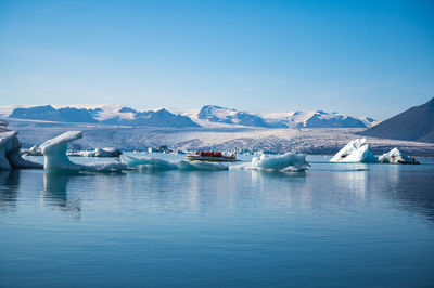 Boats in lake against sky during winter