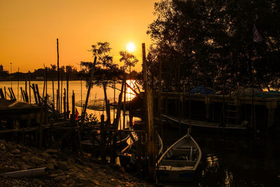 Boats moored in lake against orange sky