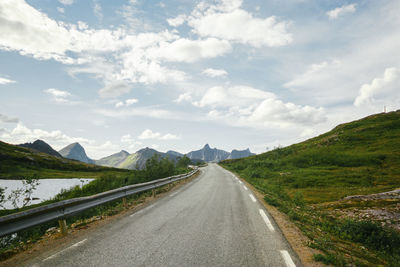 Empty road leading towards mountains against sky