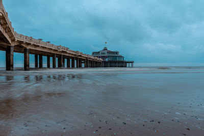 View of pier on beach against cloudy sky