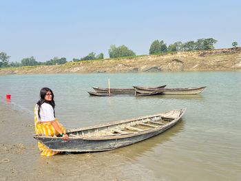 Rear view of woman sitting on boat in lake