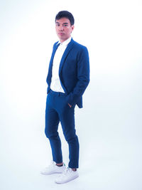 Portrait of young man standing against white background