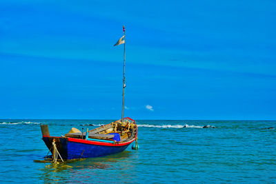 Boat moored in sea against blue sky