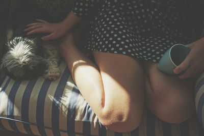 Low section of woman with puppy on sofa at home