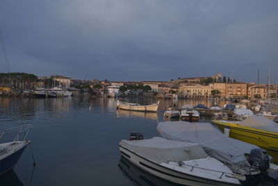 Boats moored in city against sky