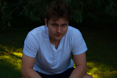 Portrait of man crouching on grassy field at park