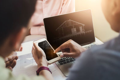 Midsection of businessmen using phone at desk in office