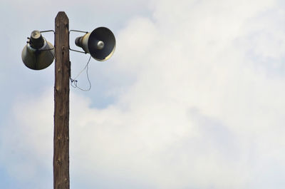 Low angle view of megaphones against cloudy sky