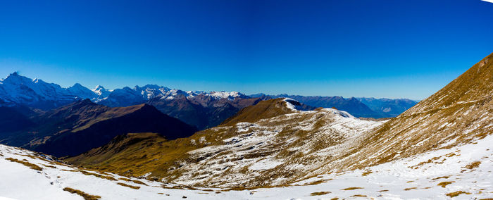 Scenic view of snowcapped mountains against blue sky